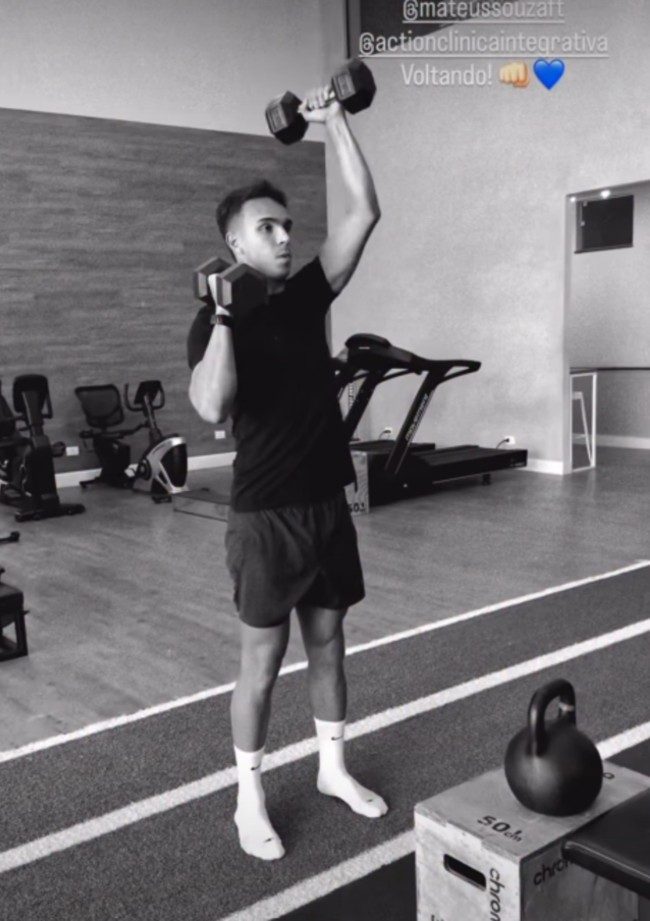 Giovane si allena in palestra con i manubri